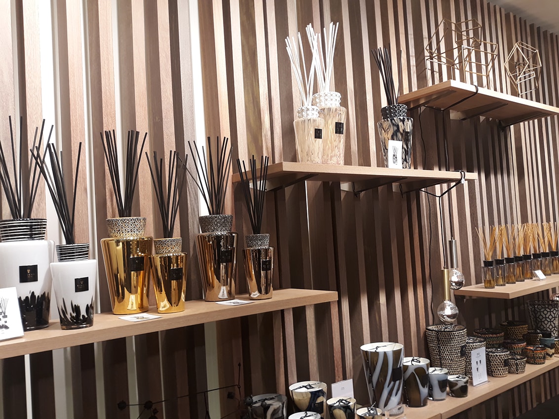 Cadeaux artisanaux pour la maison posés sur une table : bol en céramique, planche en bois et bougie coulée main