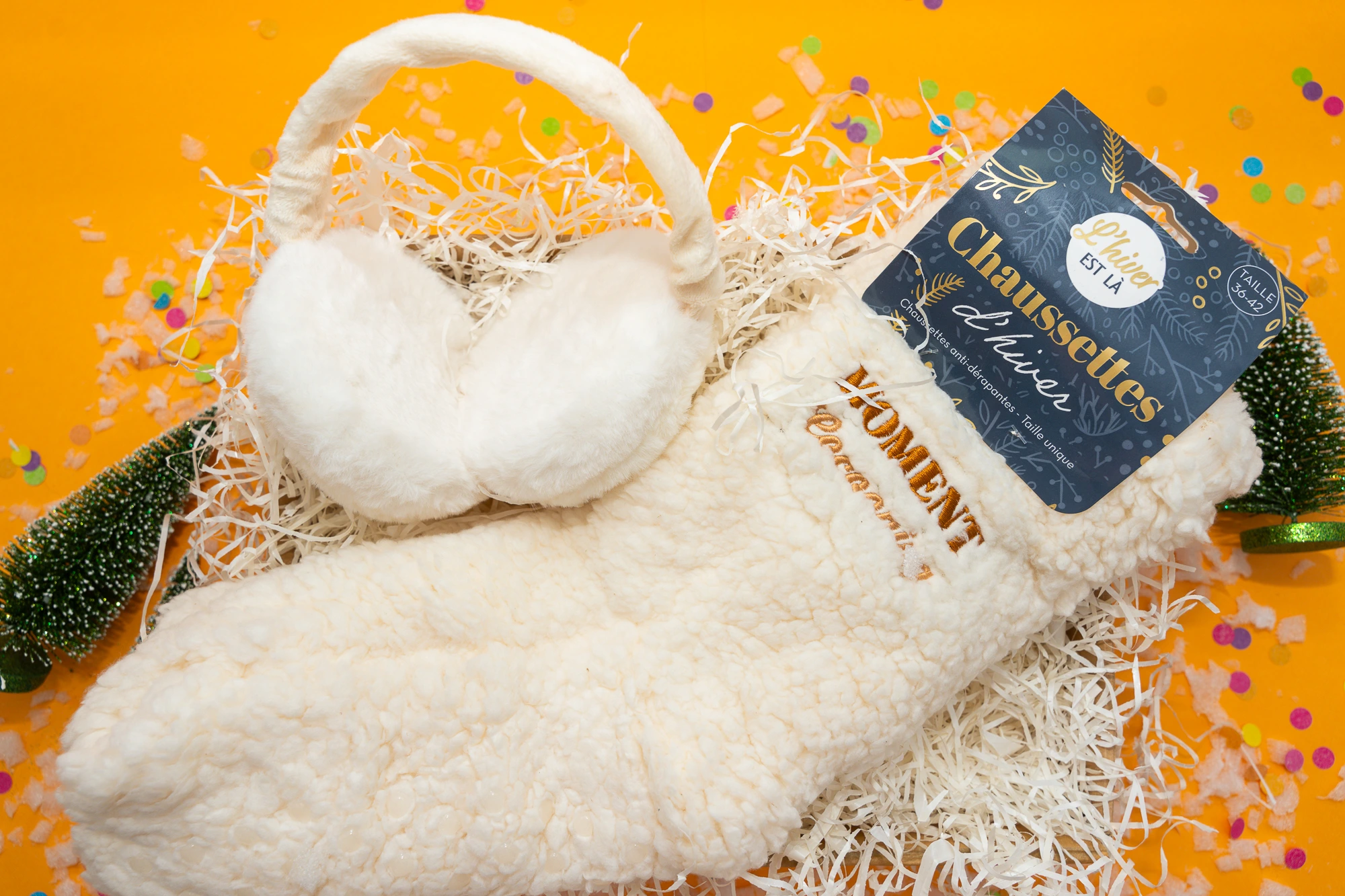 Idées cadeaux cocooning pour l'hiver avec plaid en maille, bougie parfumée et coussin moelleux